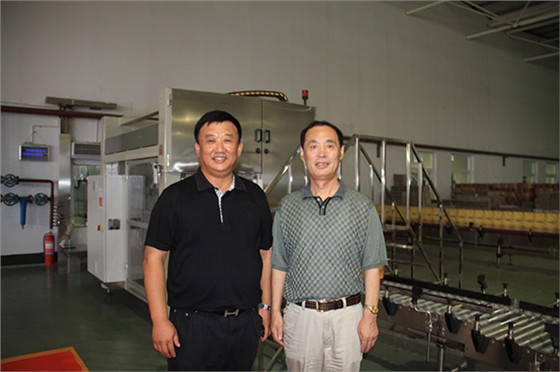 時任山東省農業(yè)廳廳長戰(zhàn)樹毅與威龍總經理孫硯田在威龍全自動灌裝生產線前合影